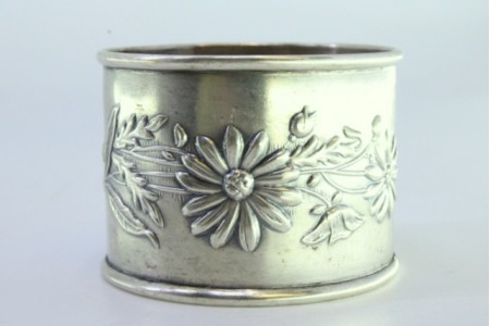 Argola de guardanapo em prata rebordada e relevada com motivos florais.